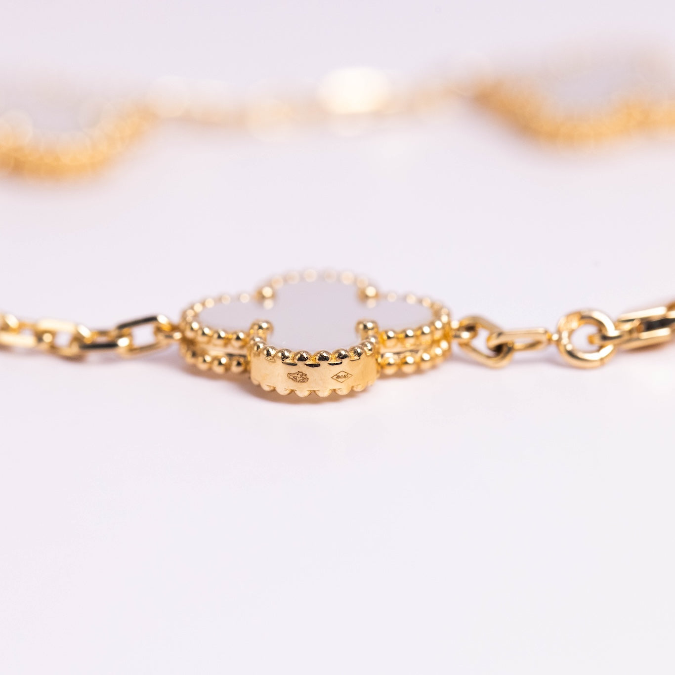 Gold bracelet with a white stone on a light background